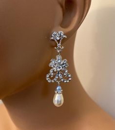 a close up of a mannequin head wearing earrings with pearls and crystals on it