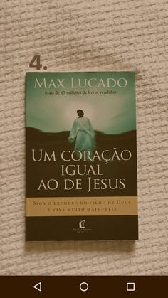 a book sitting on top of a bed next to a remote control device with the title um coracao igual ao de jesus