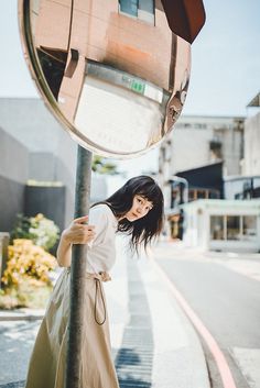 a woman standing next to a pole with a mirror on it