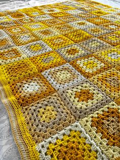 a yellow and white crocheted blanket on top of a bed