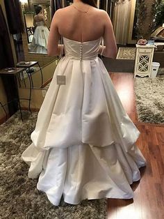 the back of a woman's wedding dress as she stands in front of a mirror