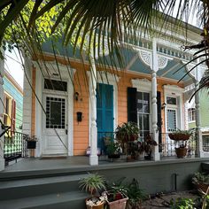 an orange house with blue shutters and potted plants on the front porch area