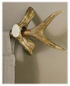 an antler mounted to the side of a wall next to a curtain tie bar