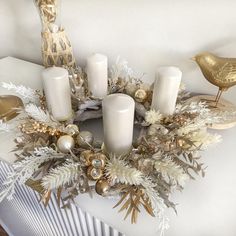 a table topped with candles and ornaments on top of a white table cloth next to a bird figurine