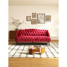 a red couch sitting on top of a hard wood floor next to a white and black checkered rug