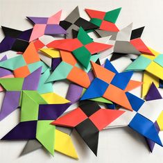 a pile of colorful origami pieces on top of a white table with scissors