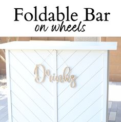 a white cabinet with the words foldable bar on wheels written in gold lettering, sitting outside