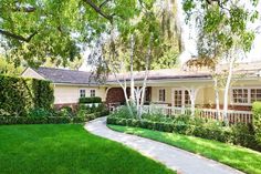 a house with green grass and trees in the front yard