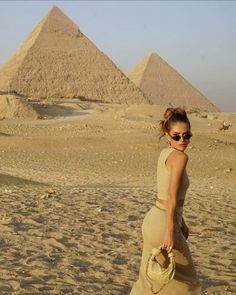 a woman wearing sunglasses standing in front of the pyramids