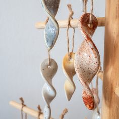 a group of sea glass hanging from a wooden pole in front of a white wall