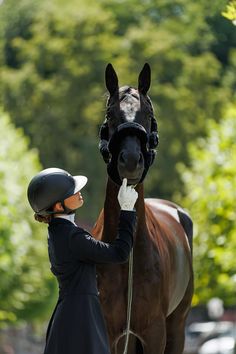 a woman standing next to a brown horse