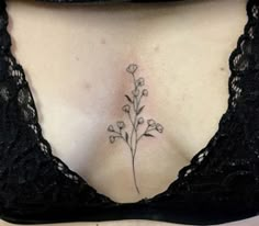 a woman's chest with a small flower tattoo on her left side ribcage