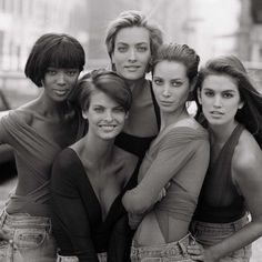 black and white photograph of four women posing for the camera with their arms around each other