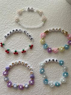 four bracelets with name charms on them sitting next to each other in different colors