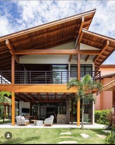 an outdoor living area with wooden roof and furniture on the grass in front of it