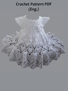 a white crochet dress with ruffles on the bottom and an openwork pattern