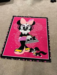 a minnie mouse quilt is laying on the floor with her name written in black and pink