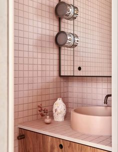 a bathroom with a sink and mirror in the corner, next to a cabinet that has two vases on it