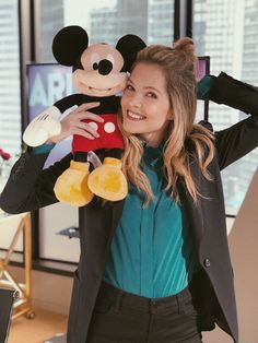 a woman holding a mickey mouse stuffed animal