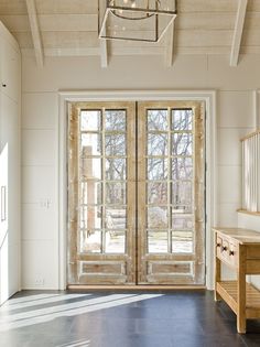 an empty room with two doors and a bench in front of the glass door that is open