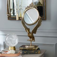 a mirror sitting on top of a table next to a book and a crystal ball