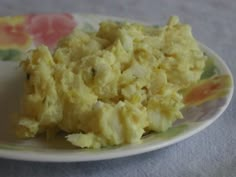 a plate with some food on it and a flowered cloth tablecloth in the background