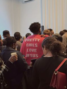 a group of people standing around each other in front of a white wall with the words pretty girls love jesus written on it