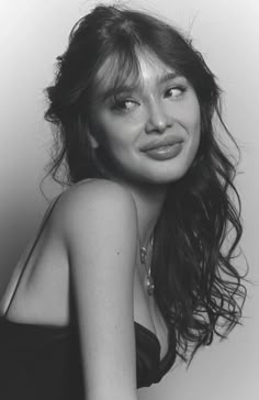 a black and white photo of a woman with her hair blowing in the wind, wearing a strapless top