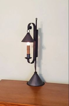 a lamp that is sitting on top of a wooden table next to a white wall