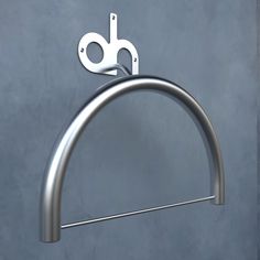 a stainless steel towel ring on a gray wall with a pair of scissors hanging from it