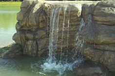 there is a large waterfall in the middle of this pond that has water coming out of it