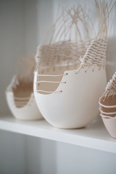 three white vases sitting on top of a shelf