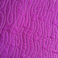 a close up view of a quilted material with wavy lines in purple and white