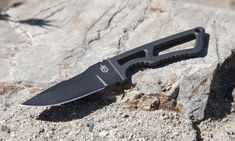 a black knife laying on top of a rock