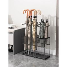 three umbrellas are hanging on a rack in front of a white wall and grey tile floor