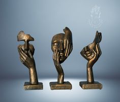 three bronze sculptures with hands holding something in each other's hand, against a blue background