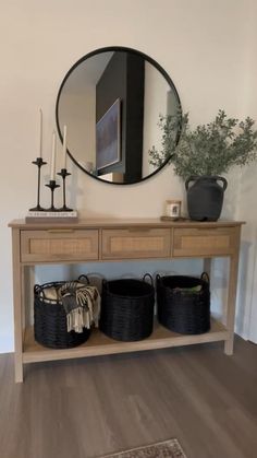 a wooden table with two baskets and a mirror on it's wall above it