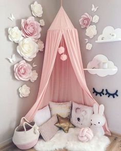 there is a pink canopy bed with flowers on the wall and stuffed animals in it