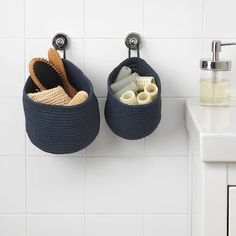 two baskets are hanging on the wall next to a sink