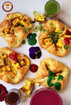 there are many small pastries on the table next to some cups and sauces