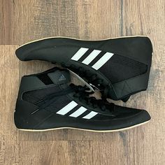 a pair of black and white shoes sitting on top of a wooden floor