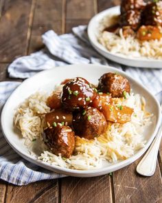 two plates filled with meatballs and rice on top of a wooden table next to a fork