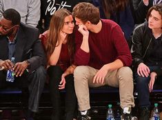 a man and woman sitting next to each other at a basketball game with water bottles in front of them