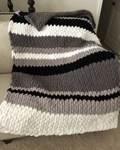 a gray and white blanket sitting on top of a couch