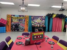 a party room decorated in pink, yellow and purple with an old school cassette tape recorder on the table