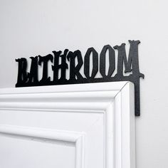 there is a metal sign that says bathroom on the wall next to a white door