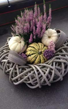 a basket filled with flowers and pumpkins on top of a car dash board next to a window