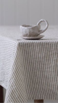 a cup and saucer sitting on top of a white table cloth covered tablecloth