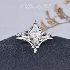 a white gold ring with a pear shaped diamond center surrounded by smaller round brilliant cut diamonds