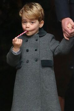 a little boy holding a candy cane in his hand